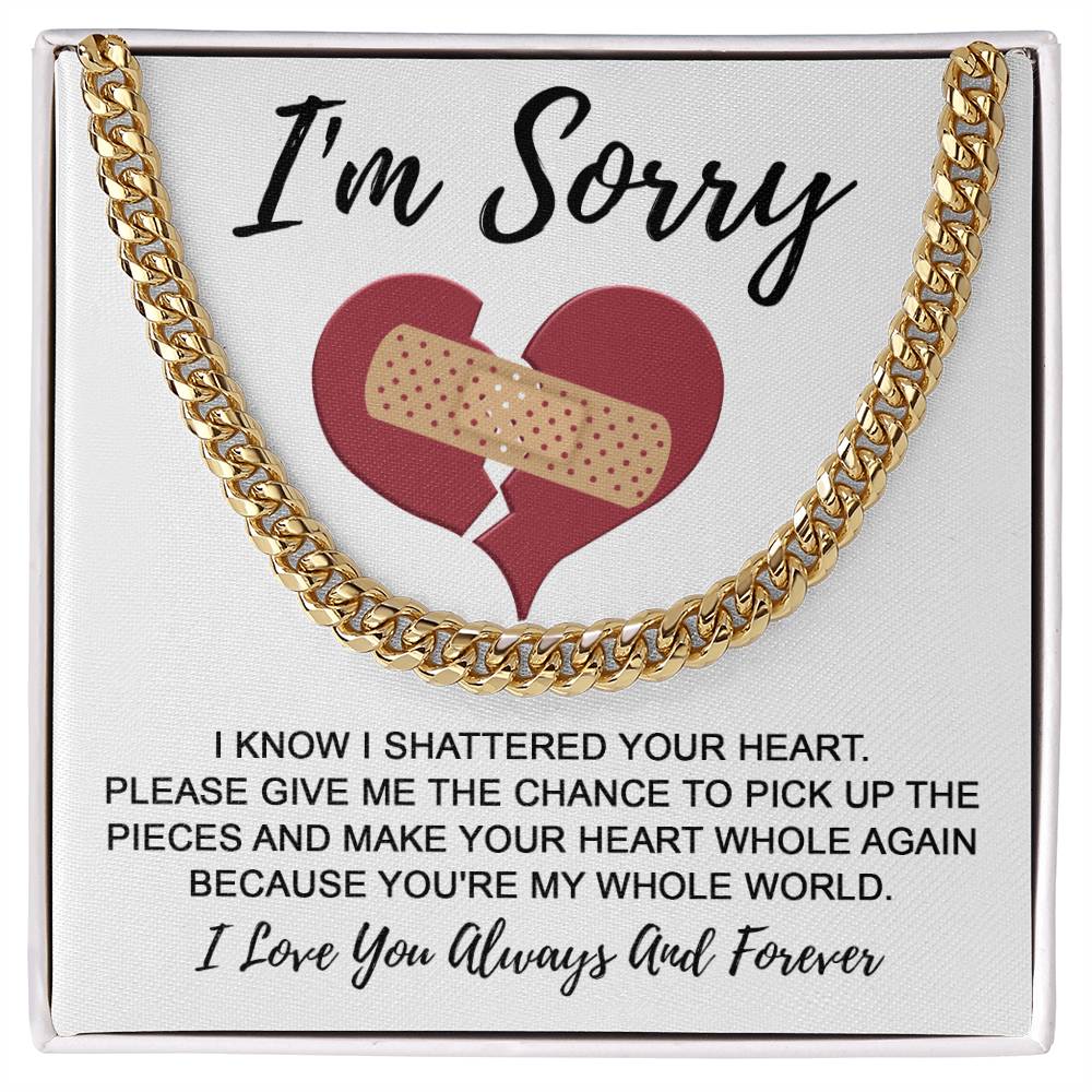 A Sorry-The Pieces - Cuban Link Chain necklace, crafted from polished stainless steel, is displayed atop a card depicting a broken heart mended with a bandage and conveying an apology message about making amends.