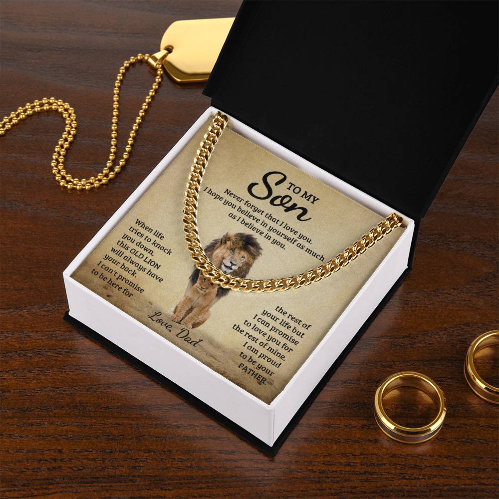 Gold necklace with a To My Son, Never Forget That I Love You - Cuban Link Chain in a gift box with a sentimental message for a son, on a wooden surface next to wedding bands. (Brand: ShineOn Fulfillment)