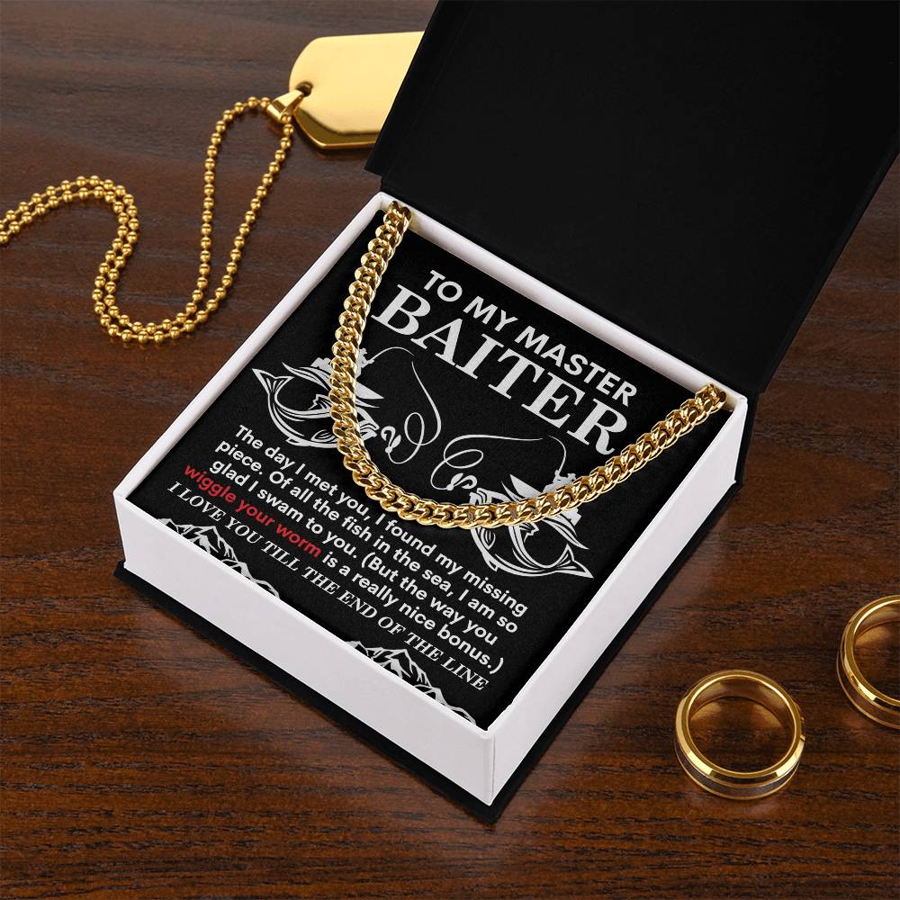 Open the black box containing the "My Man-In The Sea - Cuban Link Chain" necklace and a card with a life, joy, and love message. The box rests on wood beside gold rings and another polished stainless steel necklace.