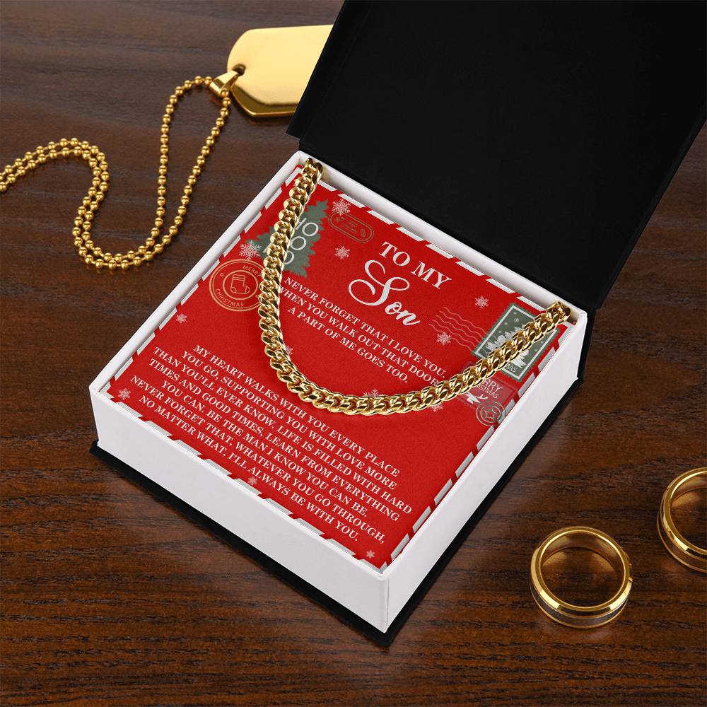 A Son-That Door - Cuban Link Chain shimmers inside an open gift box resting on a wooden table. The interior of the box carries a heartfelt message for a son. Nearby sit two gold rings and a personalized necklace, carefully selected as the ideal gifts for him.