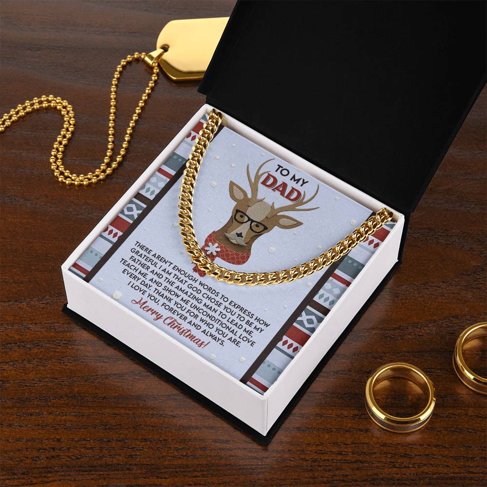 The Dad-Be My Father Cuban Link Chain is elegantly displayed on a card with a reindeer illustration, featuring the inscription "To My Dad." Accompanied by a black box lid and two gold rings on a wooden surface, it makes for an ideal gift for any occasion.