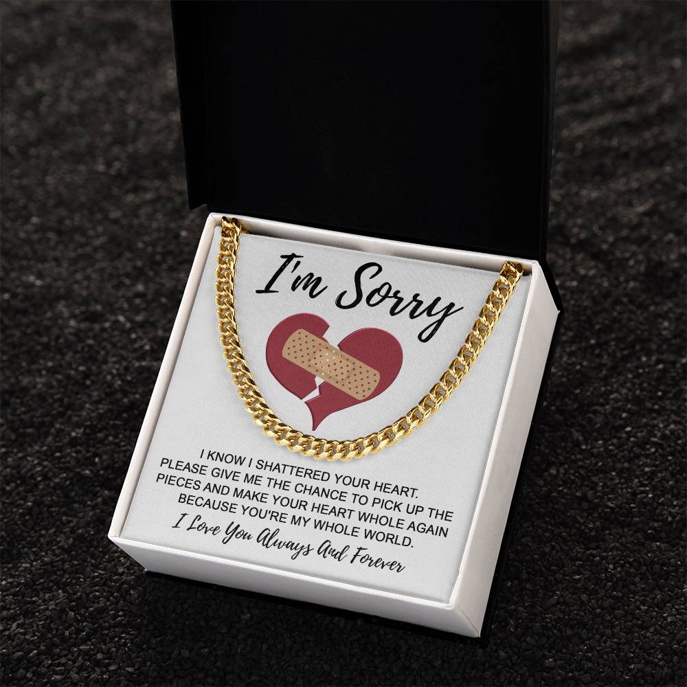 A "Sorry-The Pieces - Cuban Link Chain," crafted in 14K yellow gold, presented in a box with a heartfelt note that reads "I'm Sorry." The note features an illustration of a heart with a bandage and conveys regret for shattering your heart, asking for an opportunity to make amends.