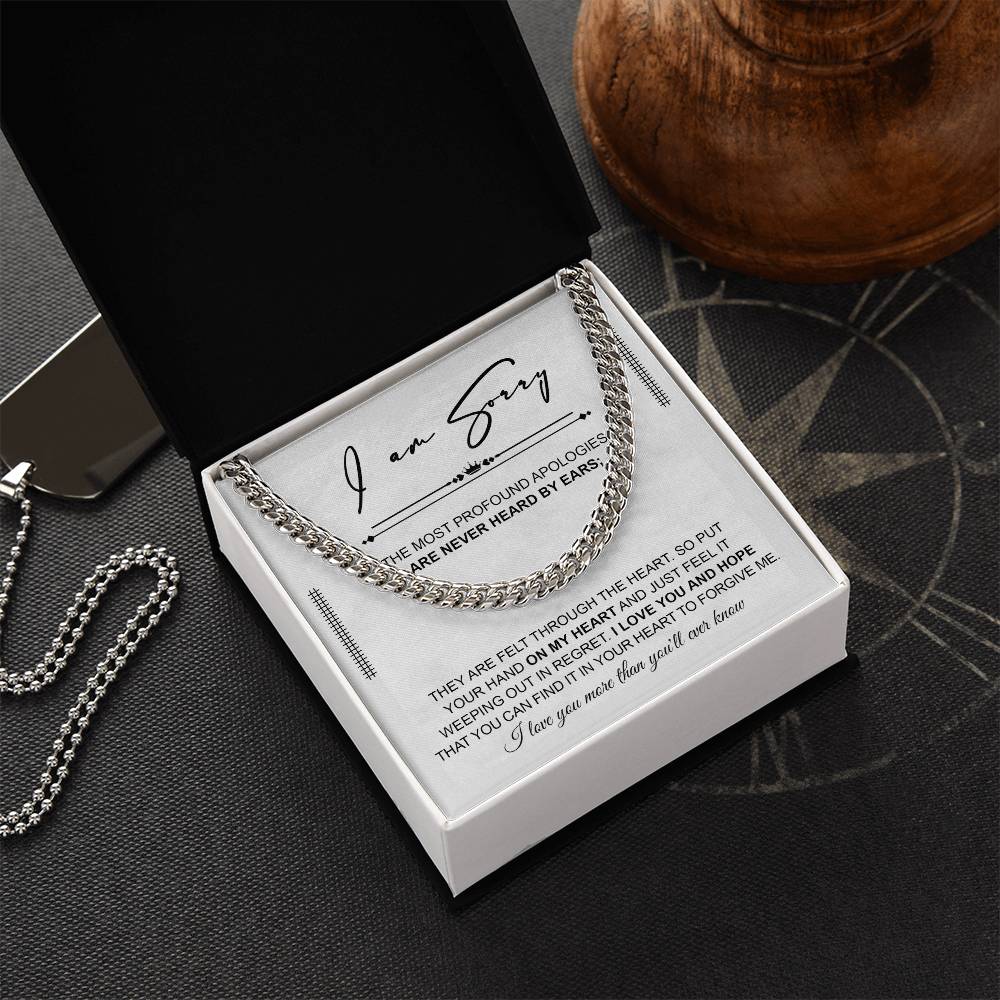 A polished stainless steel Cuban Link Chain necklace with an apology note. The note reads: "I am sorry. The most profound apologies are never heard by ears; they are felt through the heart... I love you and hope you can forgive me.