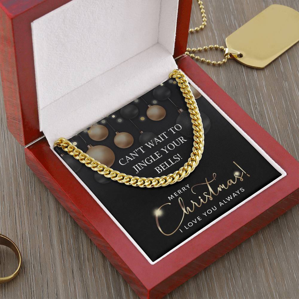 A My Man-Jingle Your Bells - Cuban Link Chain sparkles in an open red jewelry box with a note, "Can't wait to jingle your bells! Merry Christmas! I love you always." Nearby, a 14K yellow gold dog tag and ring glisten.