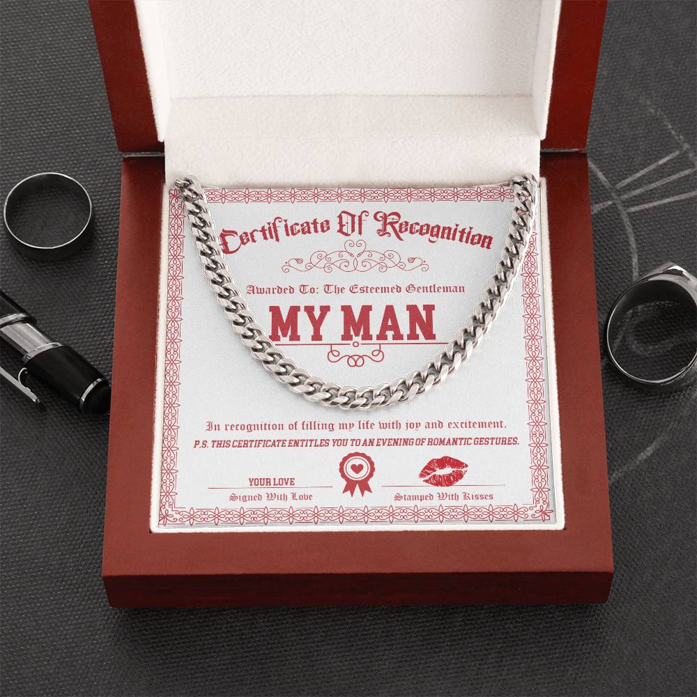 A Cuban Link Chain necklace named "My Man-Esteemed Gentleman" rests on a "Certificate of Recognition" titled "My Man," inside an open red box. Nearby, rings and a pen complete the elegant display.