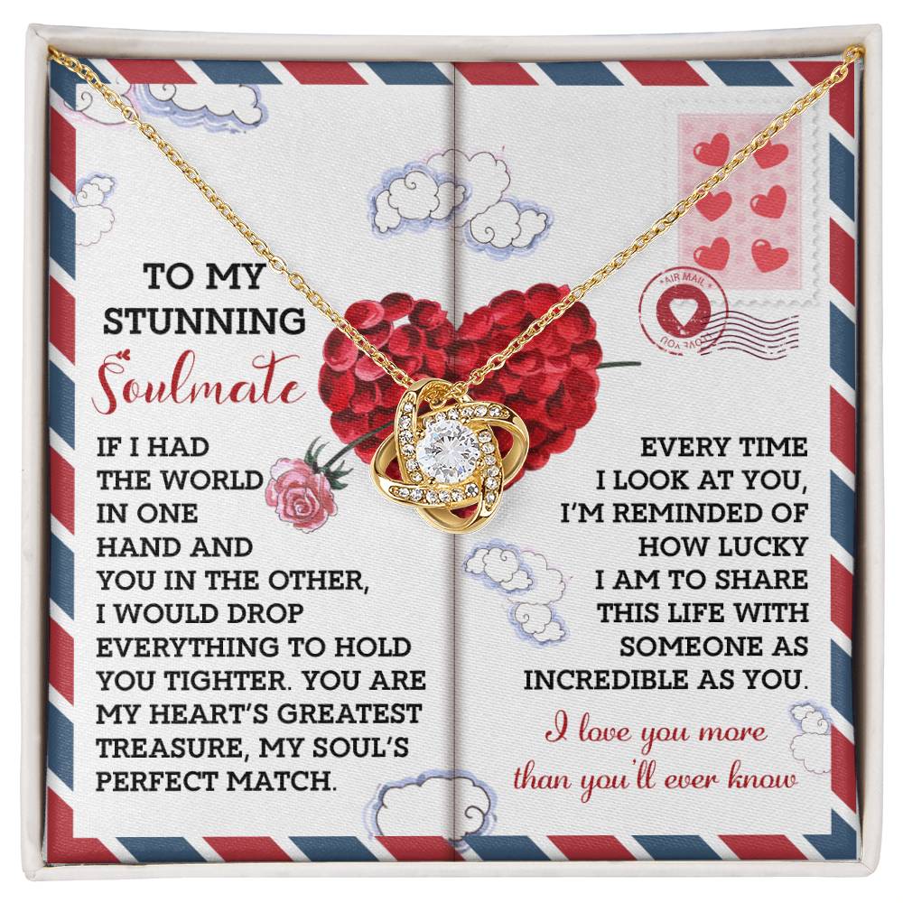 The Soulmate-Perfect Match - Love Knot Necklace showcases sparkling cubic zirconia on a gold interlocking heart pendant. It comes on a card featuring romantic love-themed illustrations and a message of love and gratitude for your soulmate.