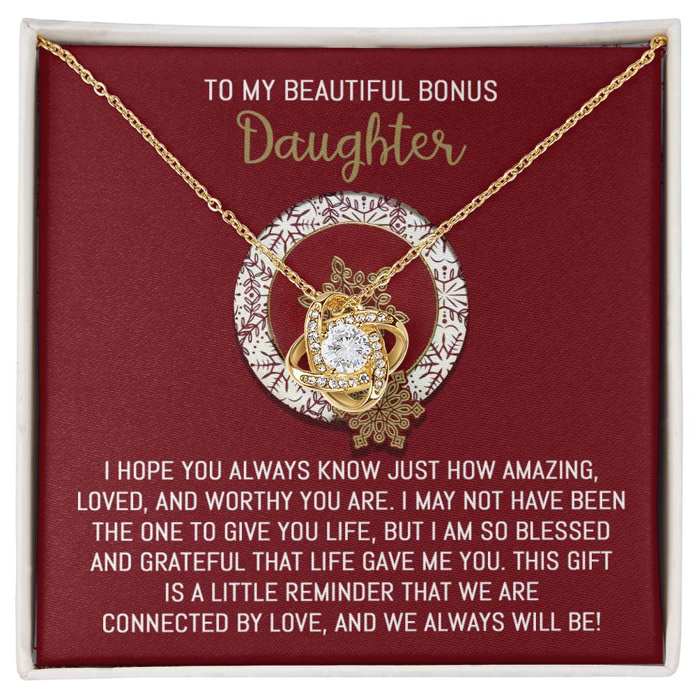 The "Bonus Daughter-Always Will Be" Love Knot Necklace glimmers with cubic zirconia crystals, nestled in a red box with a heartfelt message, making it an exceptionally personal gift for a daughter.