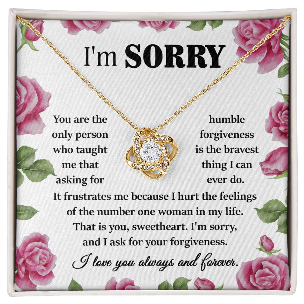 The "Sorry-Your Forgiveness - Love Knot Necklace" in 14k white gold is elegantly presented in a box adorned with pink roses. Inside, an apology message expresses regret, seeks forgiveness, and declares love.