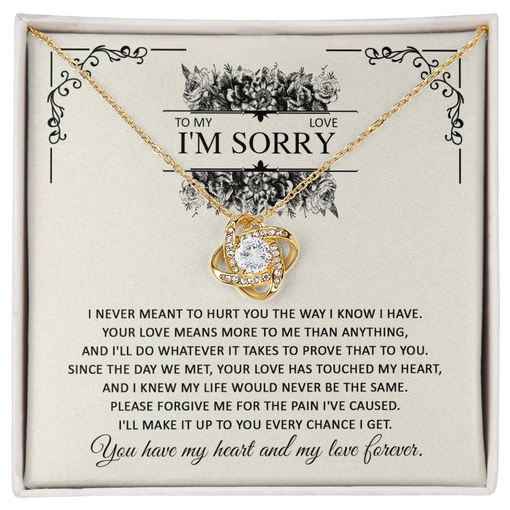 A gift box with the Sorry-Every Chance - Love Knot Necklace and an apology letter. The necklace, featuring a heart-shaped pendant with intertwined rings adorned with cubic zirconia crystals, comes in a dazzling white gold finish. The letter expresses regret and a promise of love.