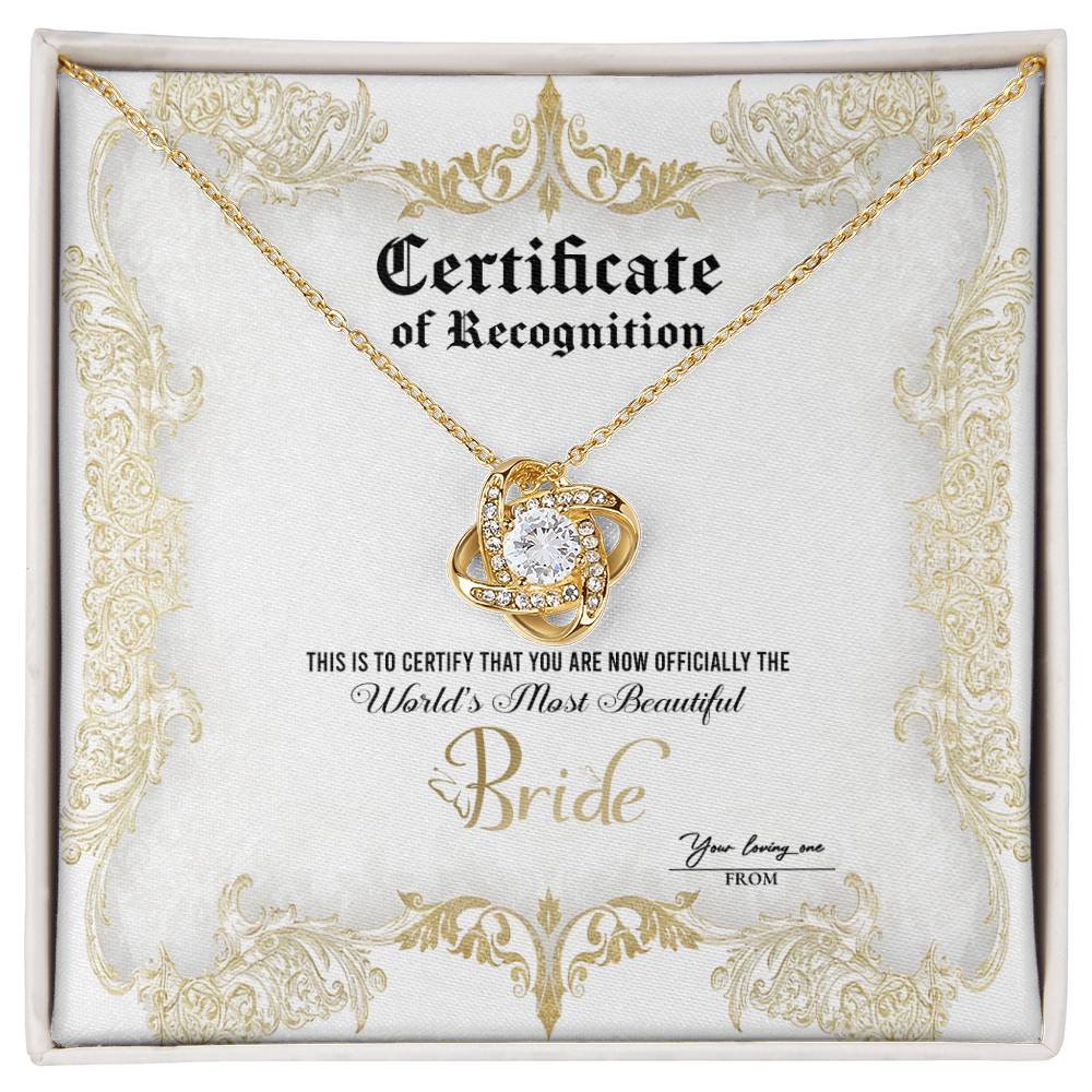 A To Bride, Certificate Of Achievement - Love Knot Necklace with a diamond-studded pendant is inside a box labeled "Certificate of Recognition" with text declaring "World's Most Beautiful Bride" and a space for names "You bring me" and "From." The pendant, set in 14k white gold, sparkles brilliantly.