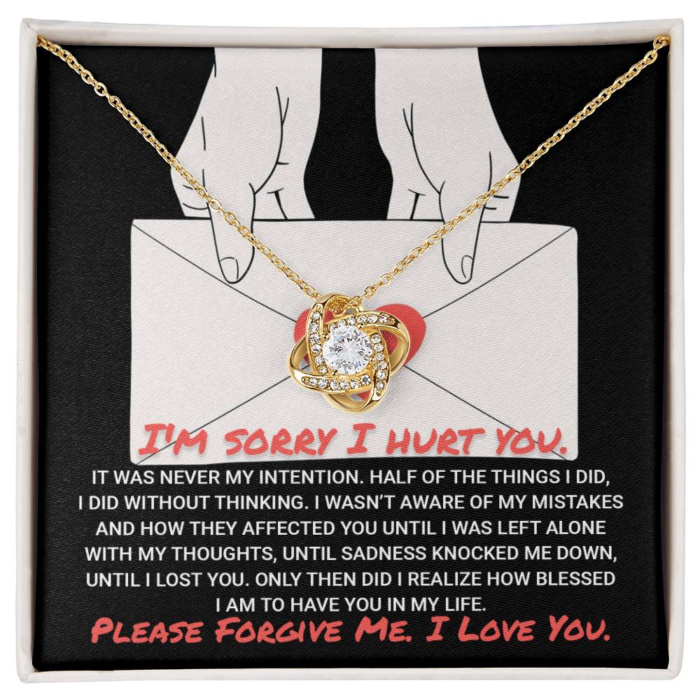 A "Sorry-Without Thinking - Love Knot Necklace" on a gold chain is displayed on a black background with an illustration of hands holding an envelope. Text reads an apology and a plea for forgiveness and love, while the sparkling cubic zirconia adds a touch of elegance.