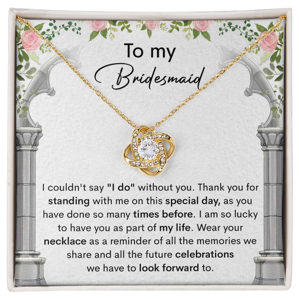 A personalized gift, the *To My Bridesmaid, Standing With Me - Love Knot Necklace* with cubic zirconia crystals, is displayed on a card that expresses gratitude to a bridesmaid, highlighting the importance of her support on the special day.