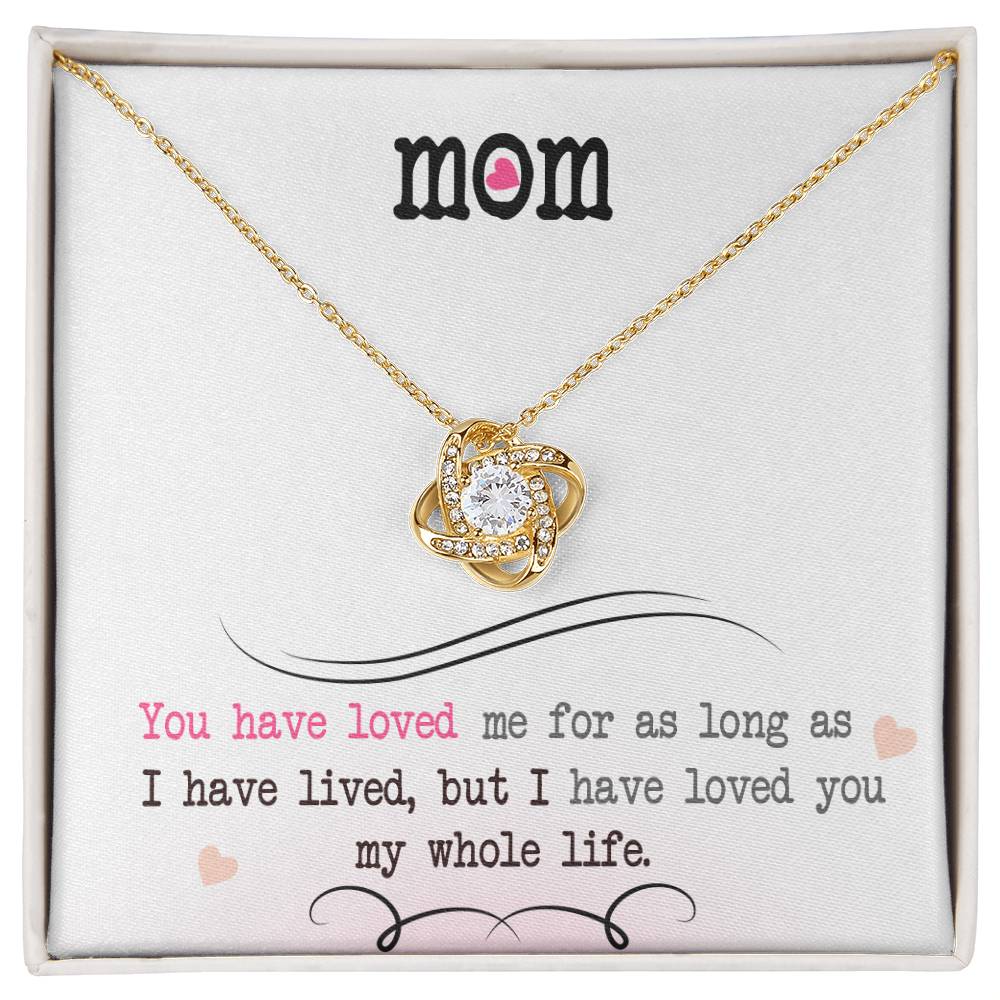 A "To My Mom, I Loved You My Whole Life" Love Knot Necklace with a heart-shaped pendant inscribed with the word "mom," presented in a box featuring a sentimental quote from ShineOn Fulfillment.