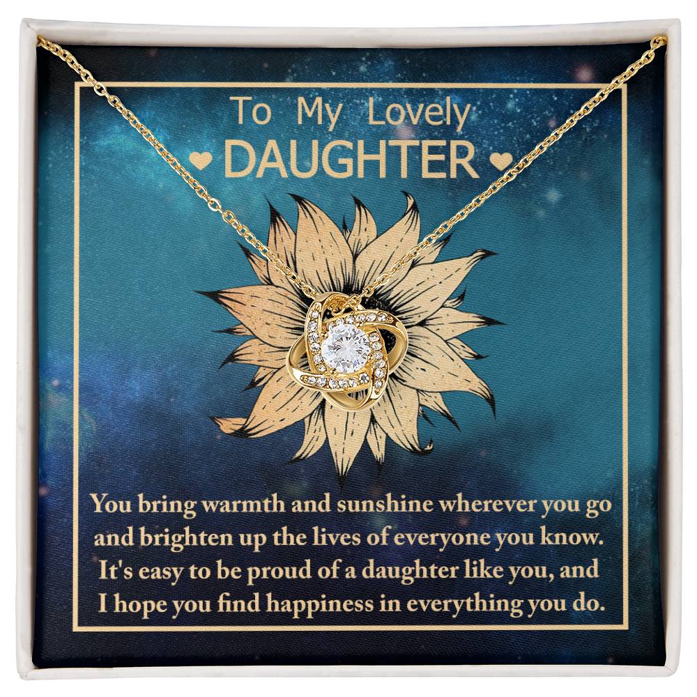 The "To Daughter, Be Proud Of - Love Knot Necklace" showcases a stunning pendant with intertwined rings adorned with cubic zirconia crystals, elegantly presented against a background featuring a sunflower and a heartfelt message to a daughter.