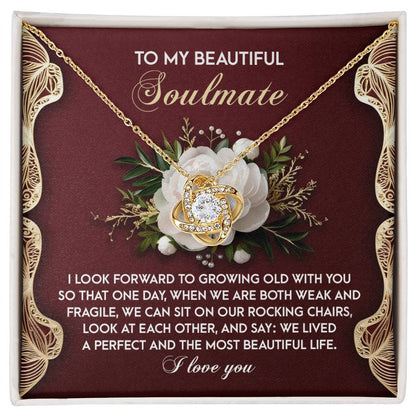 The Soulmate-Rocking Chairs Love Knot Necklace features a floral backdrop and text: "To my beautiful soulmate... I look forward to growing old with you... We lived a perfect life. I love you." This personalized gift is adorned with cubic zirconia crystals.