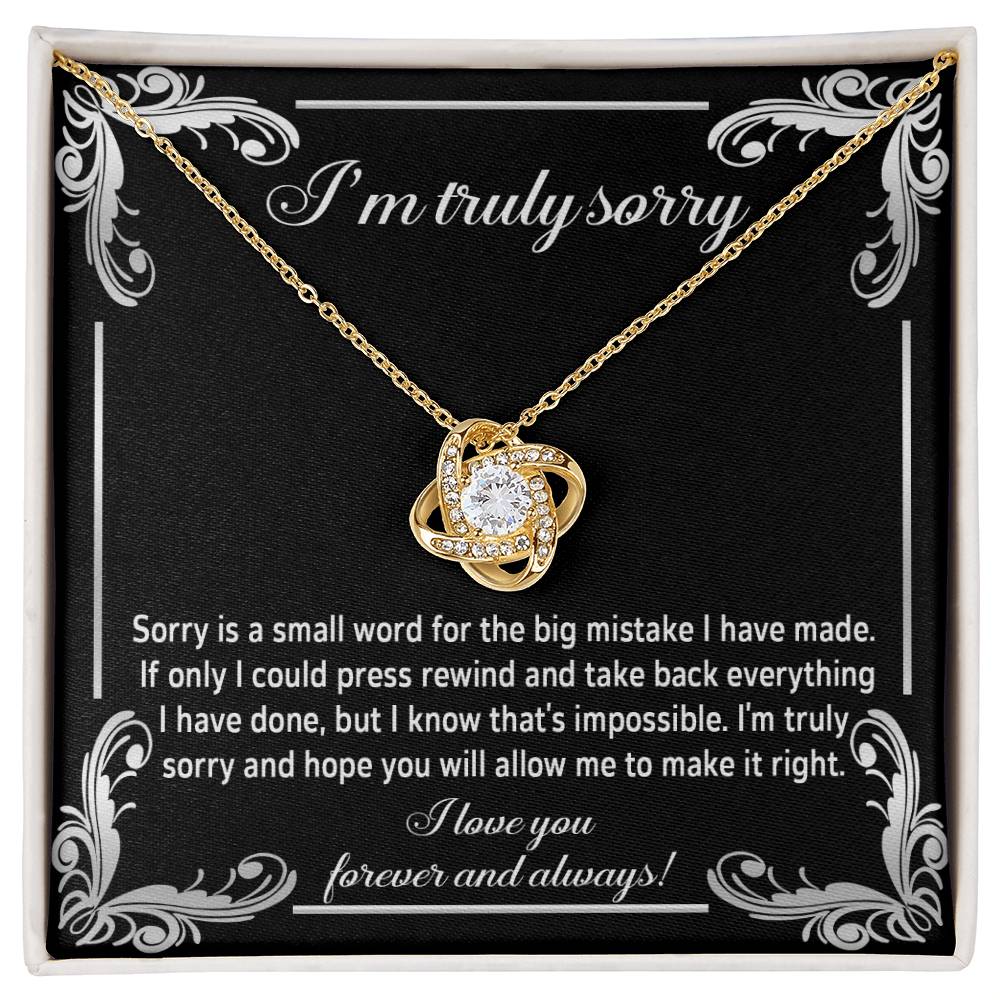 The "Sorry, Make It Right 2 - Love Knot Necklace" showcases a silver interlinked design on a black background. The backdrop features an apology message written in white text, complemented by the brilliance of cubic zirconia crystals.