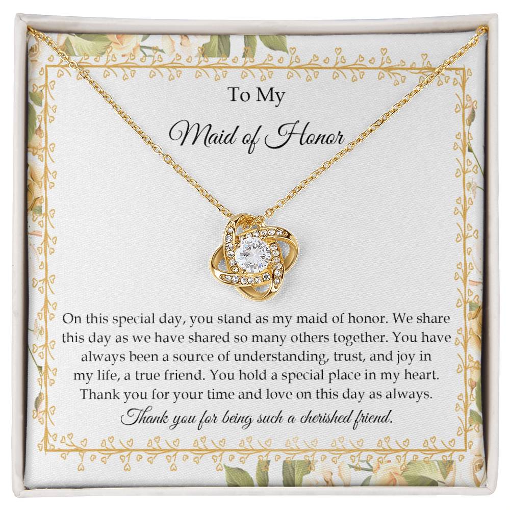 Presenting the "To Maid of Honor, Share This Day - Love Knot Necklace," featuring a stunning pendant adorned with cubic zirconia crystals and finished in white gold. It is beautifully displayed in a box embellished with a floral border and includes a heartfelt message expressing gratitude and appreciation to the "Maid of Honor.