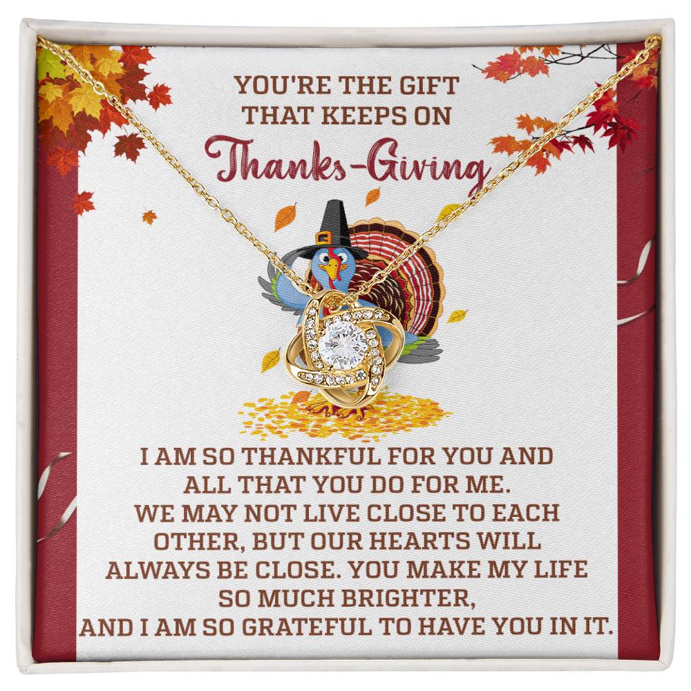 A Thanksgiving-themed jewelry display features the "Thanksgiving-Always Be Close - Love Knot Necklace," embellished with cubic zirconia crystals and accompanied by a touching message of gratitude. The scene is completed with fall leaves and a cartoon turkey wearing a pilgrim hat.