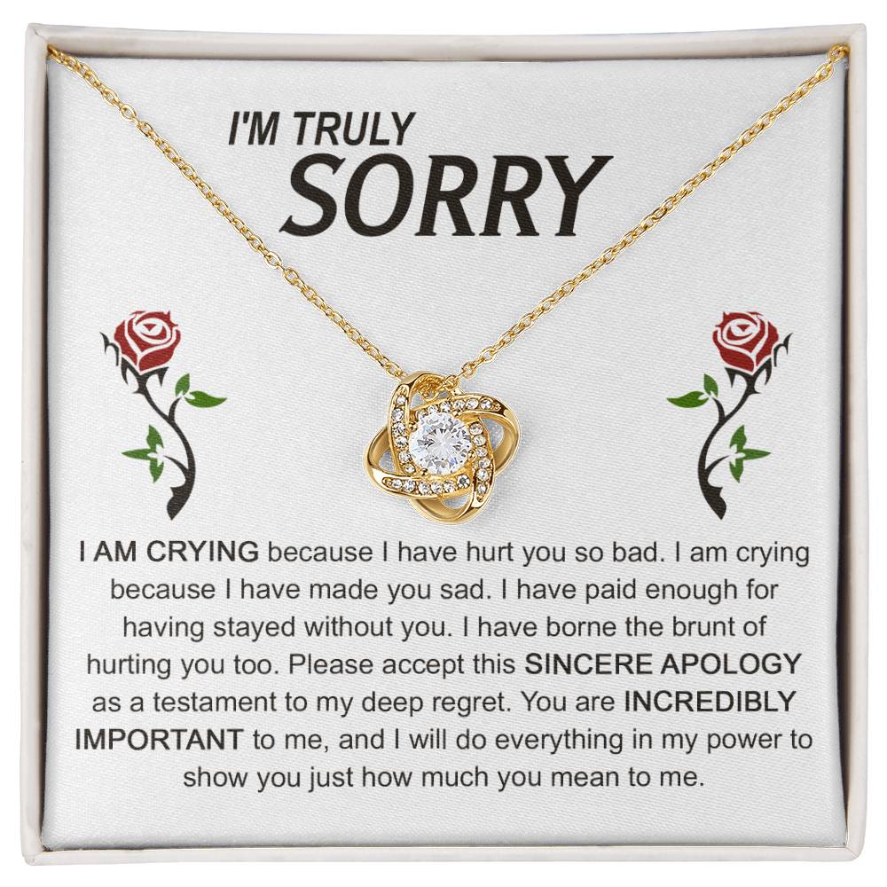 The Sorry-Made You Sad - Love Knot Necklace, crafted in silver with an interlocking design, is presented on a card featuring an apology message and accompanied by two red roses. The text conveys profound regret and vows to make things right, while the cubic zirconia crystals enhance the elegance of this heartfelt gesture.