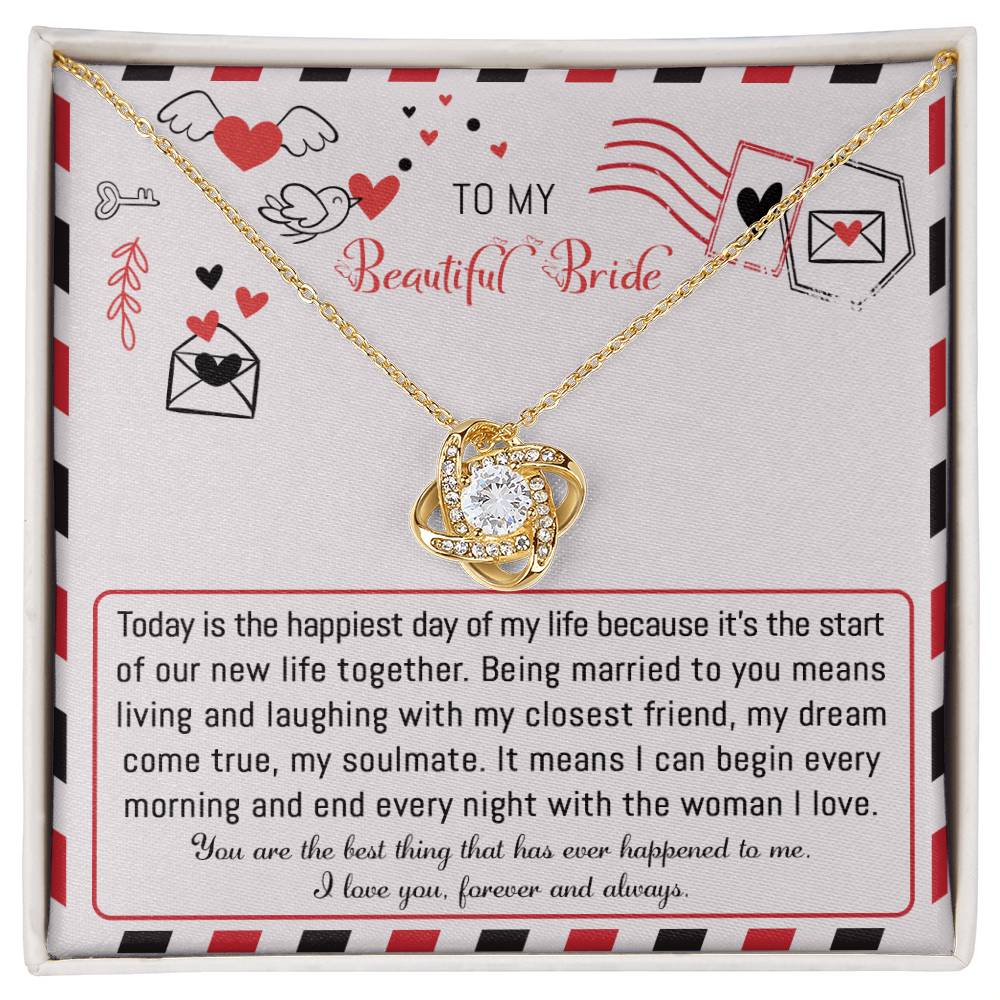 The "To Bride, The Happiest Day - Love Knot Necklace," beautifully crafted from 14k white gold and adorned with cubic zirconia crystals, is elegantly presented in a box featuring a heartfelt message for the bride, expressing love and joy for their life together.