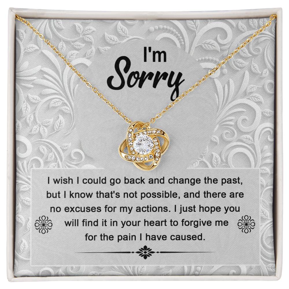 The Sorry-Change The Past - Love Knot Necklace with a white gold finish sits in a box with an apology message that reads, "I'm Sorry. I wish I could go back and change the past... I just hope you will find it in your heart to forgive me." The pendant sparkles with cubic zirconia crystals, symbolizing the unbreakable bond of love.