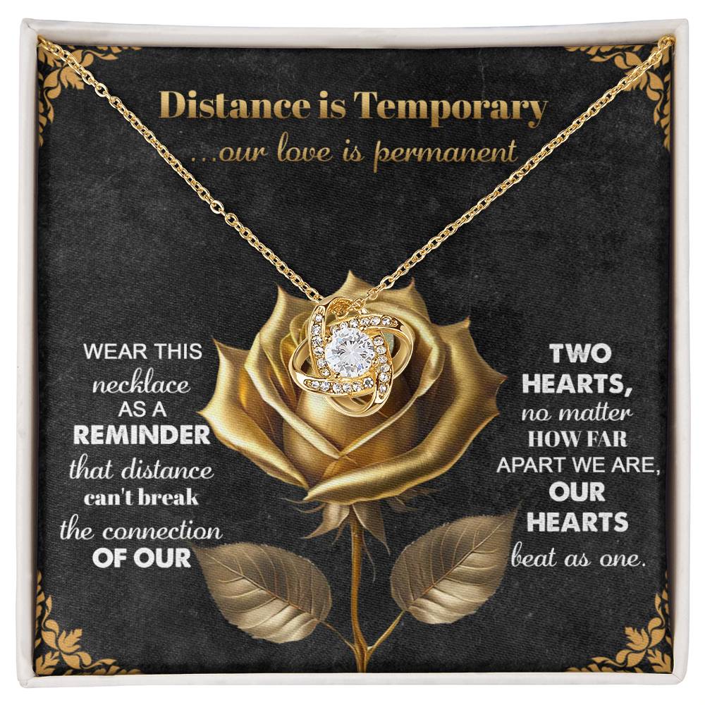 The Soulmate-Love Is Permanent Love Knot Necklace features a gold pendant with a central gem, surrounded by cubic zirconia crystals. It comes displayed on a rose-designed card with motivational love and connection text, capturing heartfelt sentiments in this personalized gift.