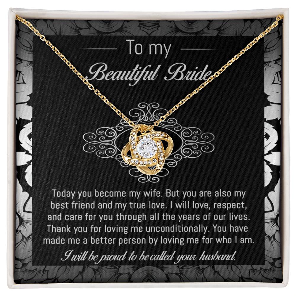 The "To Bride, My True Love - Love Knot Necklace" with a diamond pendant is displayed in a black and white box adorned with a floral pattern. The box, featuring cubic zirconia crystals, includes a heartfelt message addressed to "my beautiful bride" from her husband.