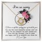 The Sorry-Make You Happy - Love Knot Necklace features a heart-shaped pendant adorned with cubic zirconia crystals, presented in a box decorated with pink flowers and the heartfelt text "I'm so sorry" at the top.