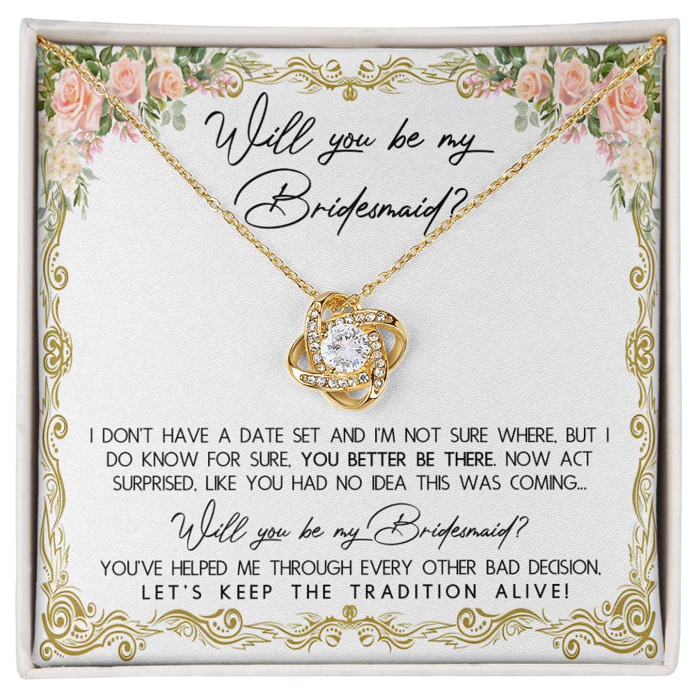 A To Bridesmaid, Keep The Tradition - Love Knot Necklace in a gift box with floral accents, featuring 14k white gold and cubic zirconia crystals. The message reads: "Will you be my Bridesmaid? I don't have a date set... act surprised. You've helped me through every other bad decision. Let's keep the tradition alive!