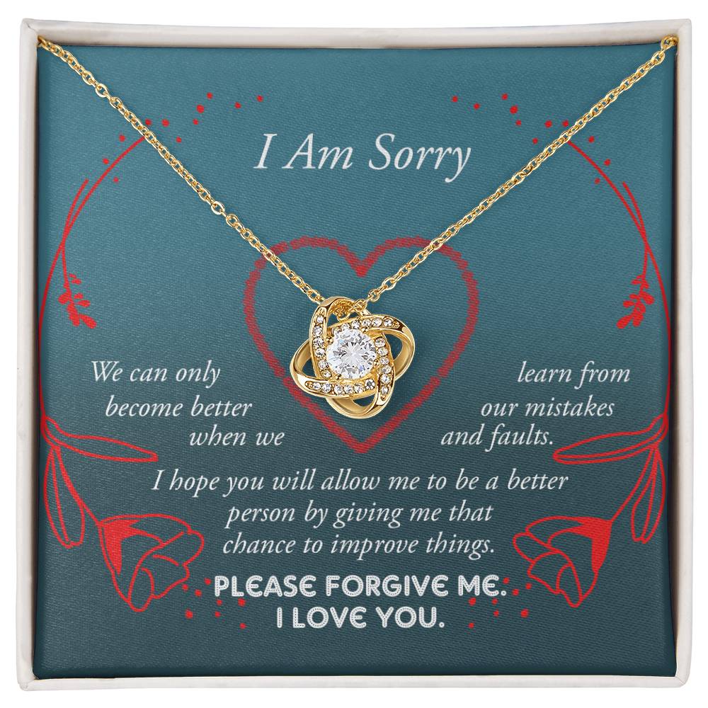 The Sorry-Mistakes And Faults - Love Knot Necklace, featuring a heart-shaped pendant with sparkling cubic zirconia set in white gold, is elegantly presented in a box adorned with the words "I Am Sorry" and a heartfelt apology message.