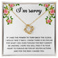 The "Sorry, Make It Right - Love Knot Necklace," featuring a silver intertwined knot pendant adorned with cubic zirconia crystals, is beautifully displayed in a box. The text on the box reads, "I’m sorry," with an apology message below, framed by a floral border in the top corners.