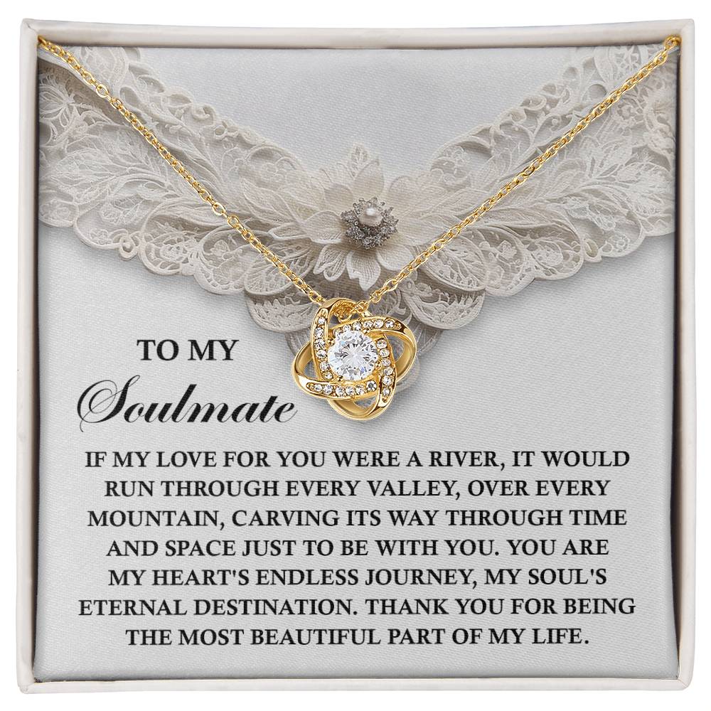 The Soulmate-Eternal Destination Love Knot Necklace sits on lace in a box. Its heart-shaped pendant and premium cubic zirconia sparkle as the love-filled message inside conveys gratitude to a soulmate, making it an ideal personalized gift.