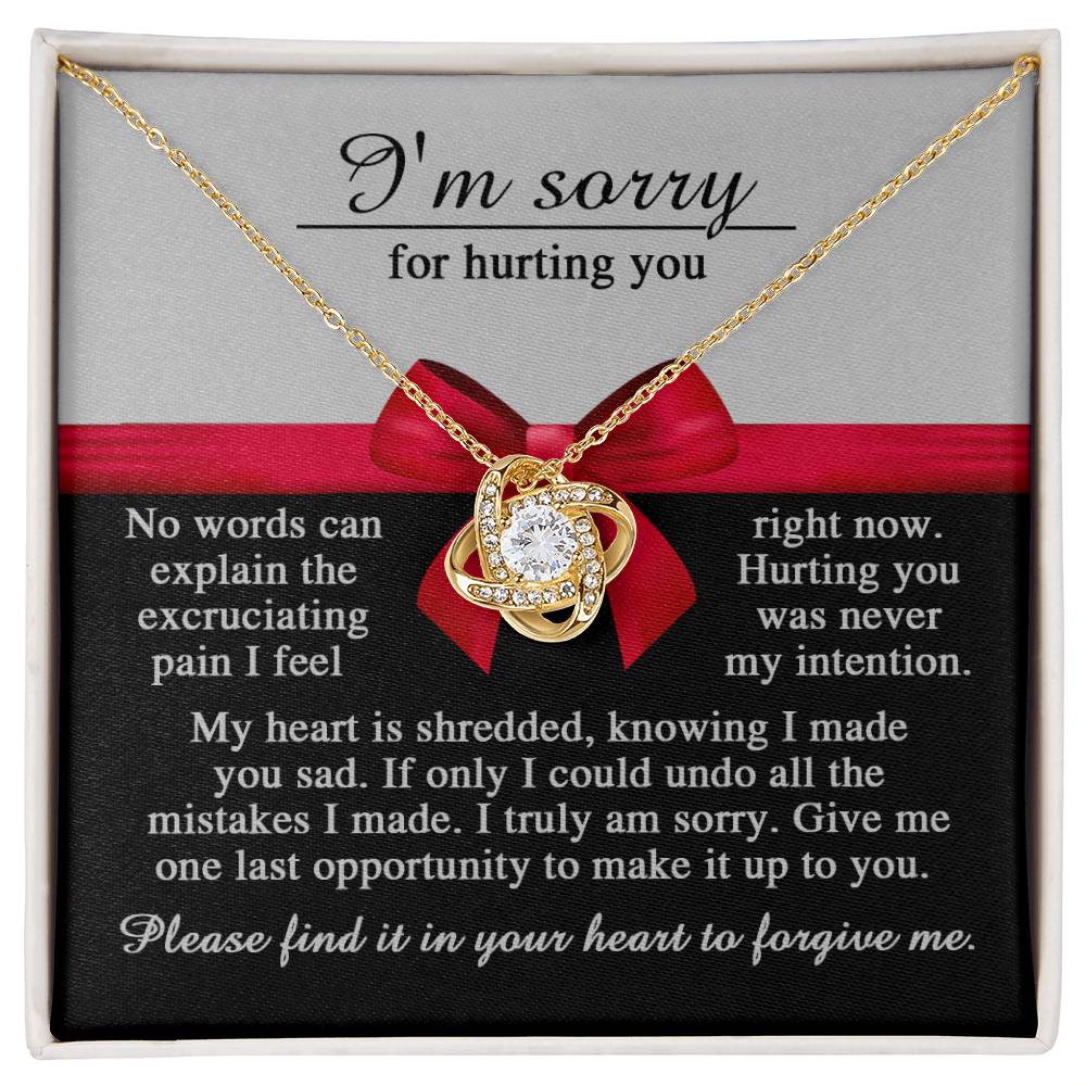 A personalized gift, the Sorry-Made You Sad - Love Knot Necklace featuring a heart-shaped pendant adorned with cubic zirconia crystals, is displayed alongside a heartfelt apology message expressing sorrow and a plea for forgiveness.