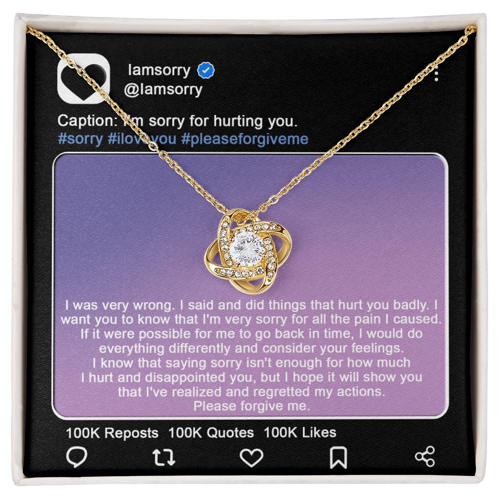 A stunning "Sorry-Hurt You Badly - Love Knot Necklace" in 14k white gold, adorned with cubic zirconia crystals, is displayed in front of a printed Instagram post that includes an apology message and hashtags like #sorry and #iloveyou.