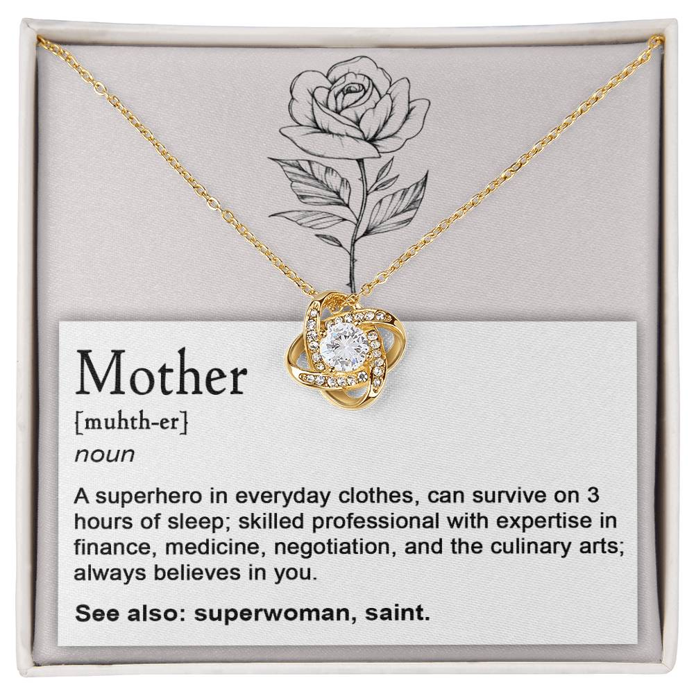 The "To Mom, Superhero - Love Knot Necklace" features a white gold finish and a pendant adorned with cubic zirconia crystals. It is displayed on a card that defines and describes the qualities of a Mother, complemented by a rose illustration at the top.