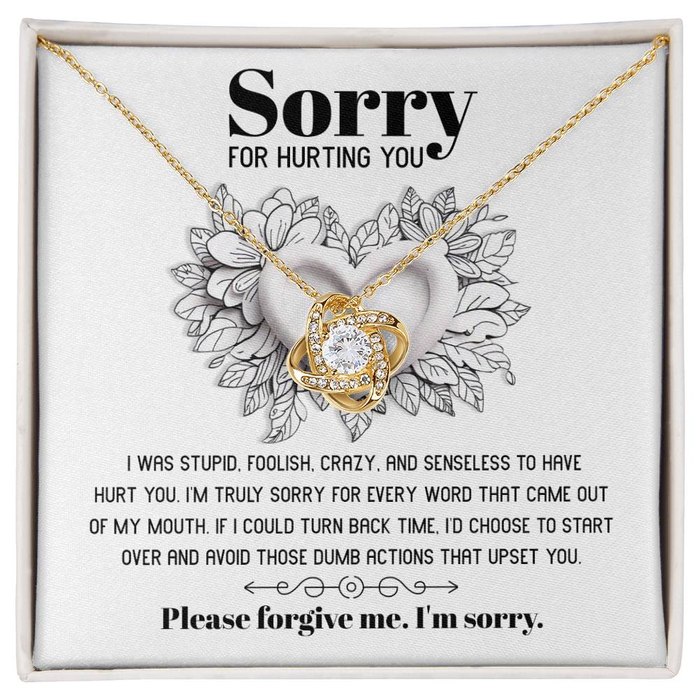 The Sorry-Turn Back Time - Love Knot Necklace, adorned with sparkling cubic zirconia crystals and featuring an intertwined pendant, is displayed on a card with the heartfelt apology message, "Sorry for hurting you," symbolizing an unbreakable bond and a request for forgiveness.