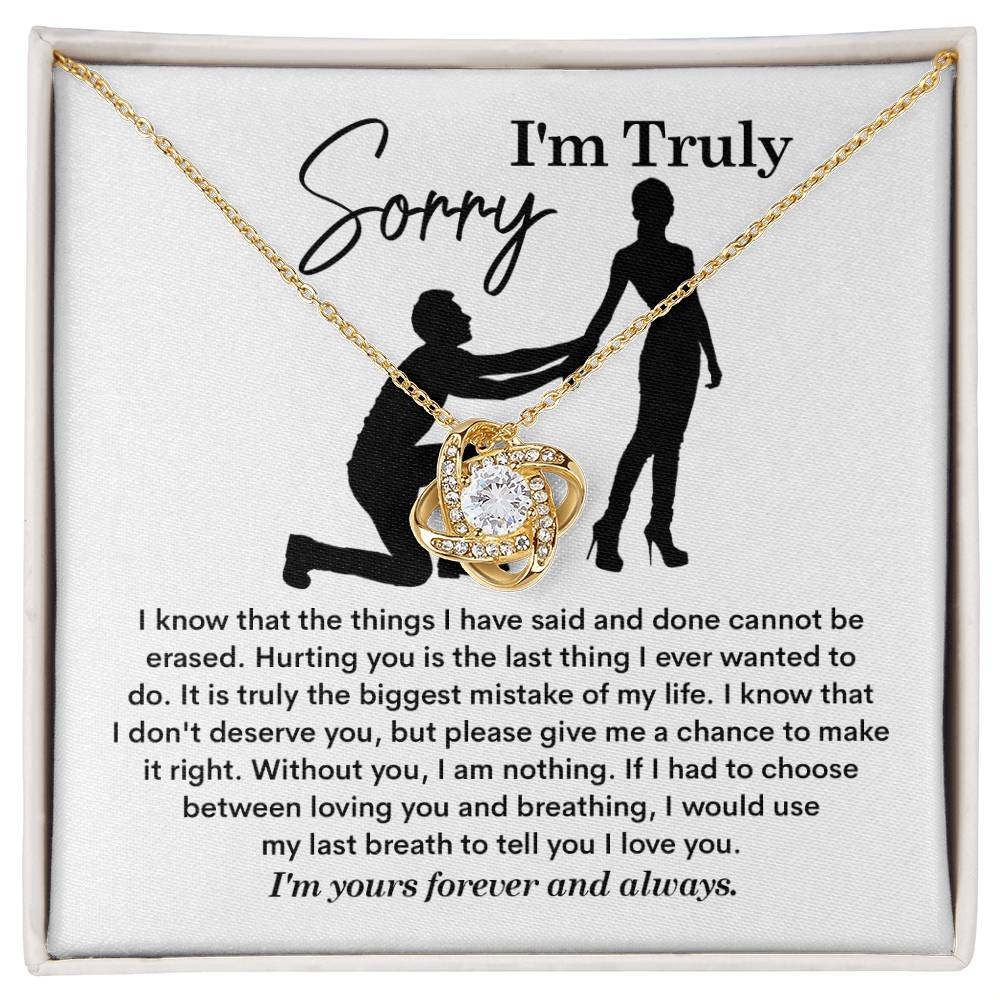 The Sorry-My Last Breath - Love Knot Necklace, a silver piece featuring an intertwined heart pendant decorated with cubic zirconia crystals, is presented on a card. The card includes an apology note with the phrase "I'm Truly Sorry" and the silhouette of one person kneeling before another.