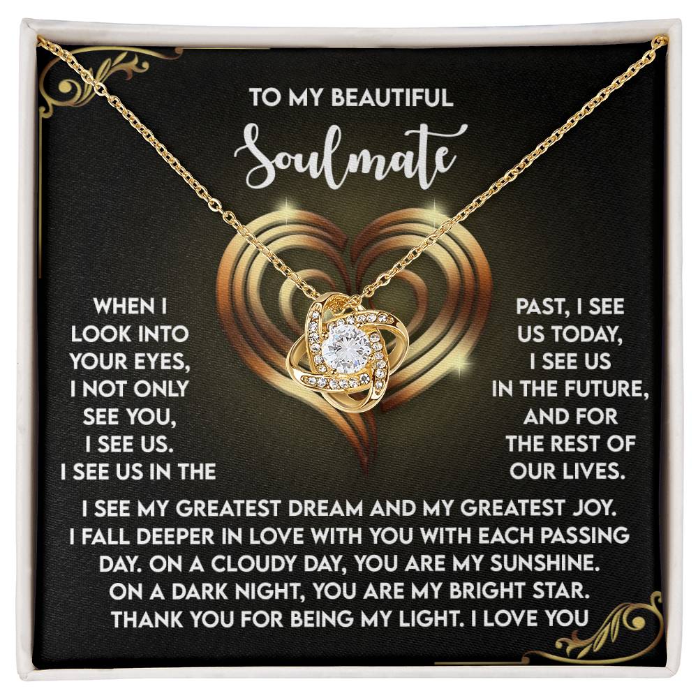 The Soulmate-I See Us - Love Knot Necklace is a gold heart-shaped pendant with a clear gem on a card. Featuring intertwined hearts and romantic text, the necklace expresses love and devotion while the white or yellow gold finish evokes timeless charm with cubic zirconia crystals.