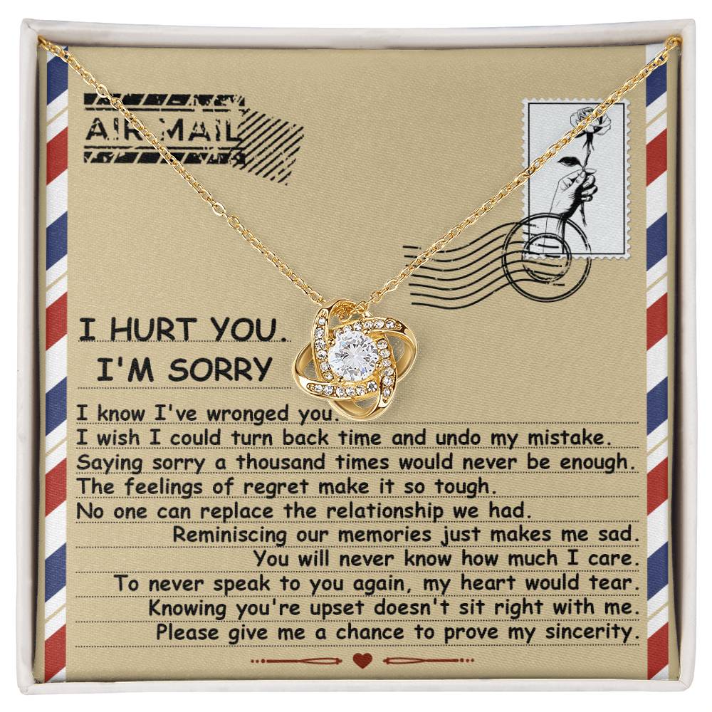 The Sorry-Makes Me Sad - Love Knot Necklace comes in a box and features a heart-shaped pendant adorned with cubic zirconia crystals set in a stunning gold finish. It includes an envelope-themed note expressing regret and asking for forgiveness, complete with heartfelt text and an "Air Mail" graphic at the top.