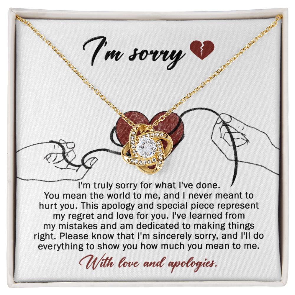 The Sorry-Mean The World - Love Knot Necklace, crafted from white gold and adorned with a heart-shaped pendant, is displayed on a card. This card conveys an apology message expressing regret and dedication to making things right, ending with "With love and apologies." The necklace is embellished with sparkling cubic zirconia crystals that add a touch of elegance.