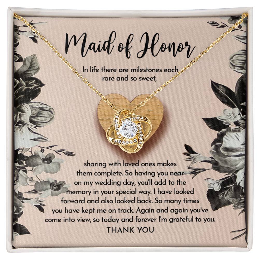 The "To Maid of Honor, My Wedding Day - Love Knot Necklace" features a heart-shaped pendant on a card titled "Maid of Honor," with a heartfelt message about milestones, love, and gratitude. The pendant is available in white gold or yellow gold finish and is adorned with sparkling cubic zirconia crystals.