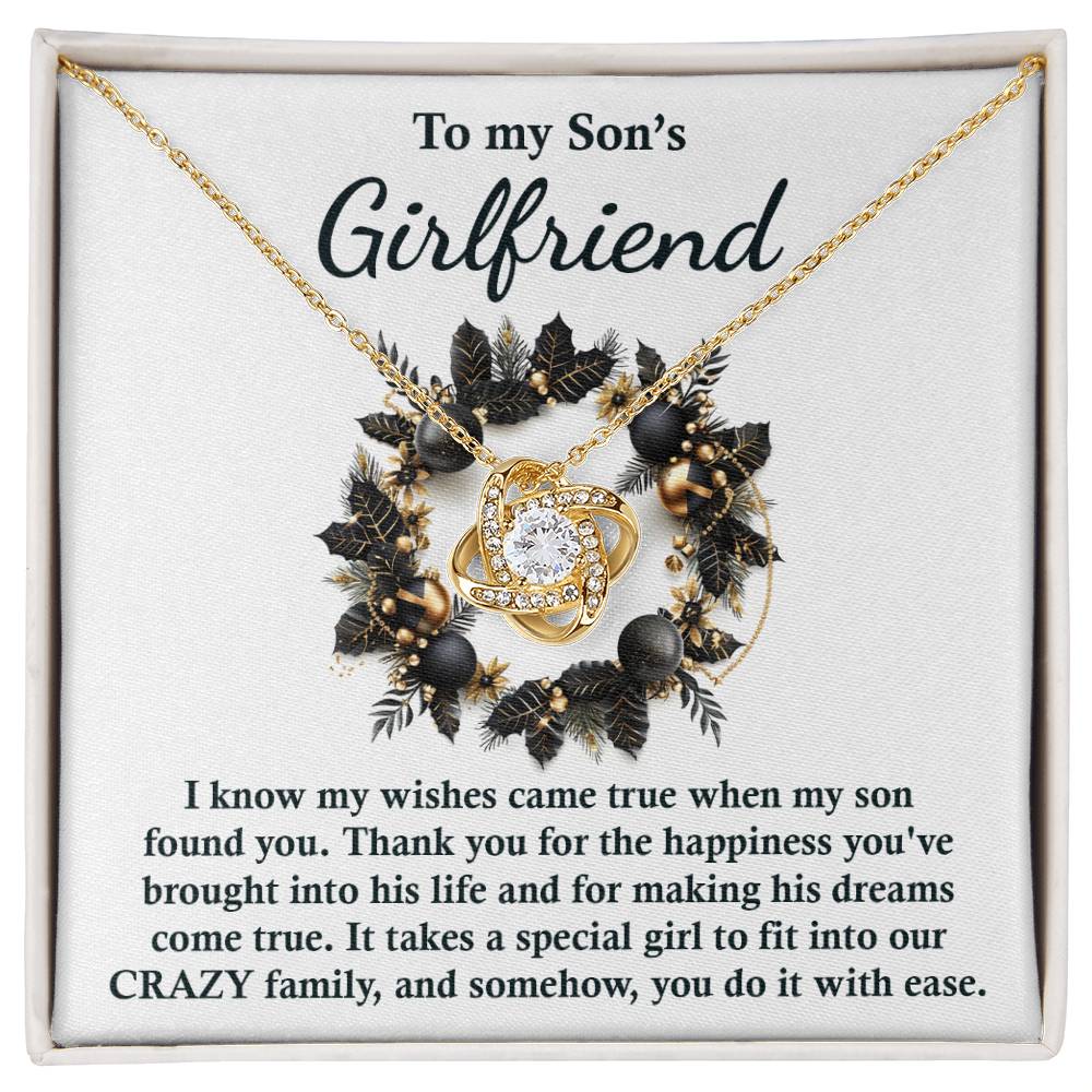 The Son's Girlfriend - Found You - Love Knot Necklace, featuring a heart-shaped pendant and presented on a card with the message "To my Son's Girlfriend," expresses gratitude and acceptance, making it an excellent personalized gift.