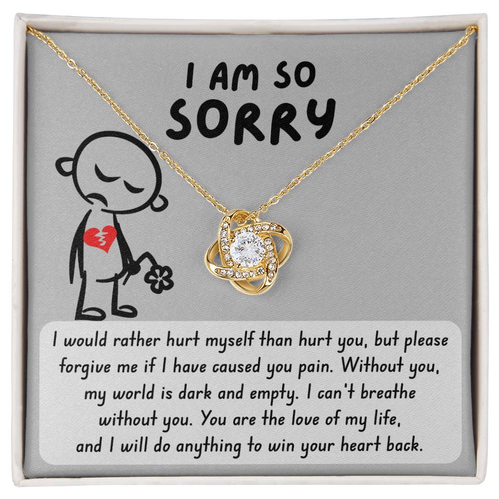 The "Sorry-Dark And Empty - Love Knot Necklace" with a gold finish and a decorative pendant is displayed in a box featuring a sad cartoon character holding a flower, accompanied by a heartfelt apology message underneath.