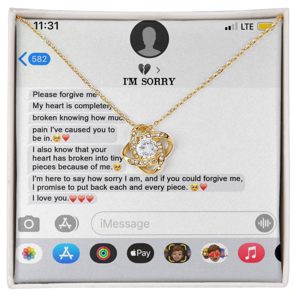 The "Sorry, Completely Broken - Love Knot Necklace" features a gold finish and sparkling cubic zirconia crystals, displayed atop a printed text message conversation that conveys an apology and expresses love.