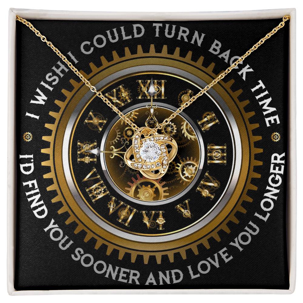 The "To Wife, Turn Back Time - Love Knot Necklace," adorned with cubic zirconia crystals, is elegantly displayed against a clock design backdrop. The text around the clock reads, "I WISH I COULD TURN BACK TIME, I'D FIND YOU SOONER AND LOVE YOU LONGER.