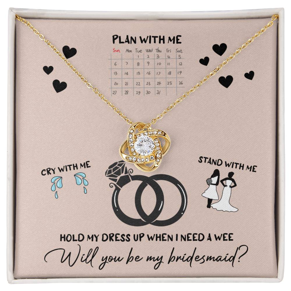 A To Bridesmaid, Will You Be 2 - Love Knot Necklace, adorned with cubic zirconia crystals, is displayed on a card featuring a calendar, wedding rings, and bridesmaid-related illustrations. The text reads, "Will you be my bridesmaid?" Choose from a white gold or yellow gold finish to make the moment even more special.