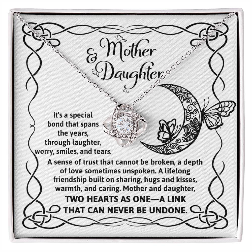 A silver To Daughter, A Special Bond - Love Knot Necklace with an intertwined knot pendant adorned with cubic zirconia crystals, presented on a card with "Mother & Daughter" text, a decorative border, and a heartfelt message about their unbreakable bond.