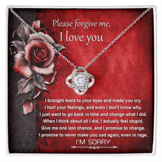 The "Sorry-One Last Chance - Love Knot Necklace" showcases an interlocking design and is elegantly displayed on a card featuring an apology message and images of red roses. Decorated with shimmering cubic zirconia crystals, this personalized gift is set against a red background with black floral accents.