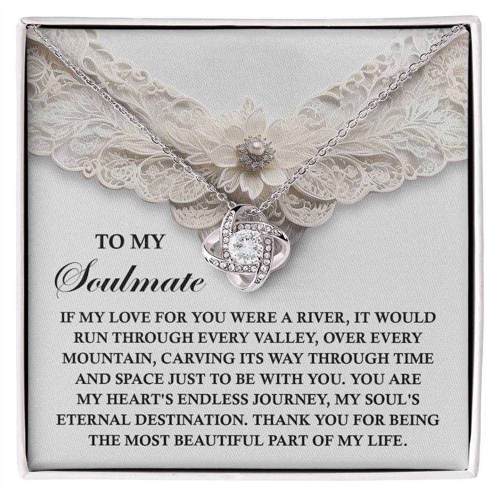 The Soulmate-Eternal Destination - Love Knot Necklace features an intricate design on a lace background with a heartfelt message about love and soulmates in black text, adorned with cubic zirconia crystals and available in elegant white gold or yellow gold finish.