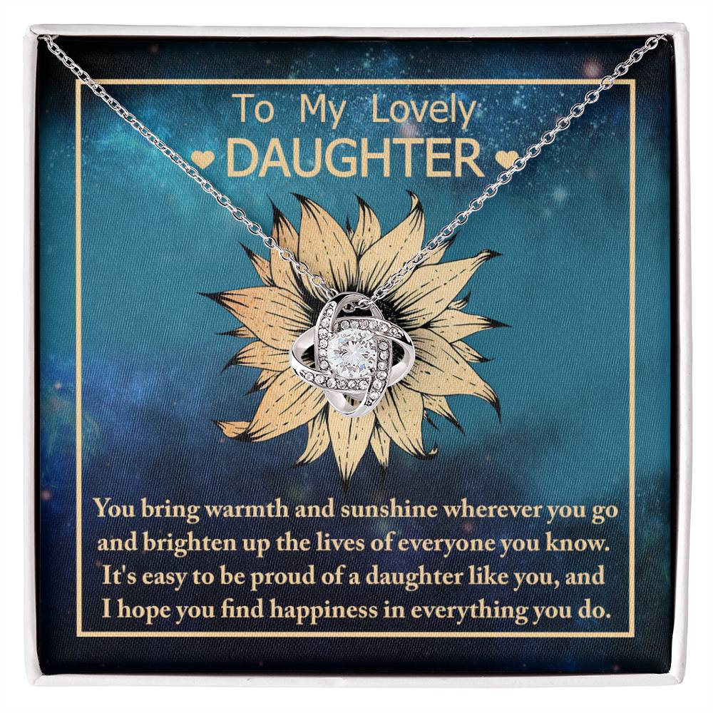 The "To Daughter, Be Proud Of - Love Knot Necklace" showcases a stunning pendant with intertwined rings adorned with cubic zirconia crystals, elegantly presented against a background featuring a sunflower and a heartfelt message to a daughter.